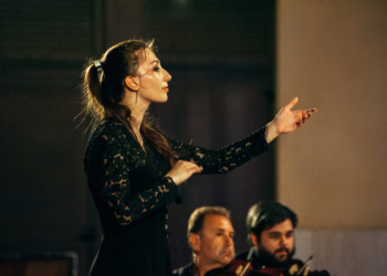 Una direttrice d’orchestra sul podio per un ensemble tutto maschile